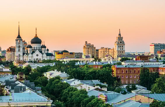 A cityscape of Voronezh, Russia, with several churches and buildings visible at sunset